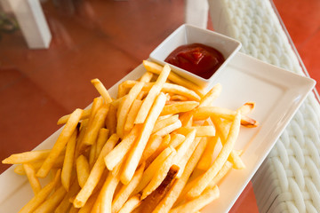 French fries, chili sauce, on a glass table.
