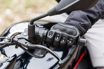 Biker sitting on motorcycle, close-up view on hands on handlebar