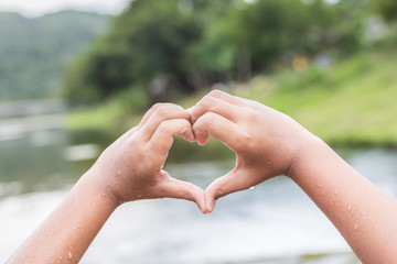 Wet hands with heart sign at the river in Thailand