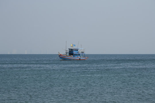 Thai fish boat in the sea with skyscrapers of Pattaya as a background