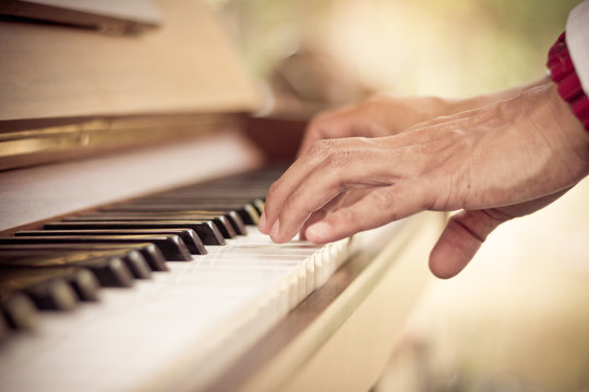 Close up man hand musician playing piano vintage tone.