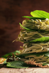 Dried pasta with fresh spinach, old wooden background, selective