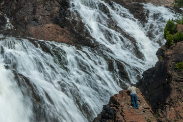 large waterfall with tourist taking photo from rockface