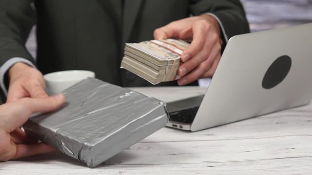 Businessman pulling a cocaine brick from under his desk and selling it to a dealer.