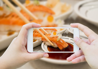 Taking photo of Grilled salmon sushi in chopsticks
