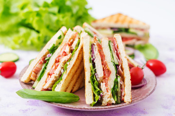 Club sandwich with chicken breast, bacon, tomato, cucumber and herbs