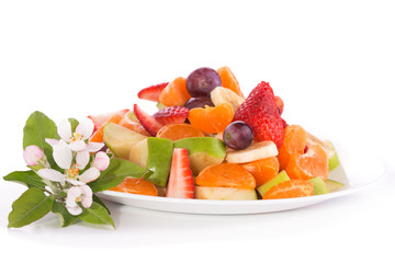 Fruit salad on a plate, with apple blossoms next to it