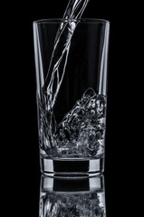Pouring water in glass on black background