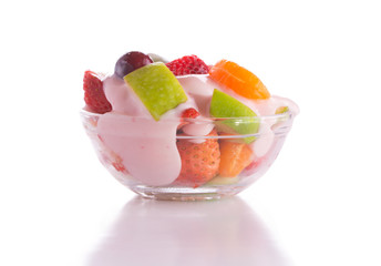 Nutritiousbreakfast with fruit salad topped with pink strawberry yogurt in a glass bowl, on white background