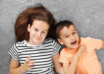 Brother and sister lying on carpet