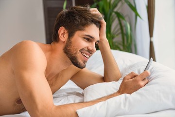 Carefree guy messaging on mobile phone at home