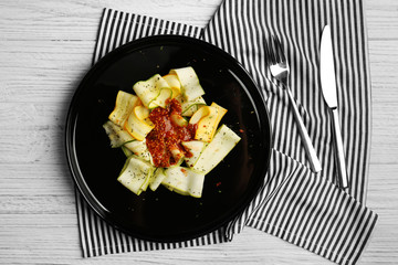 Slices of zucchini with seasoning on black plate