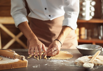 Man preparing pasta on kitchen table, close up view
