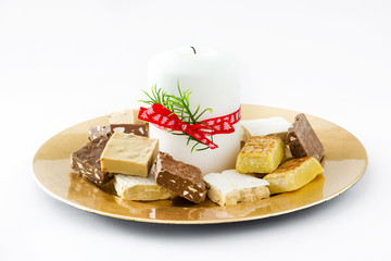 Christmas nougat and white candle on a golden plate isolated
