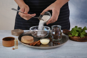 Woman making coffee body scrub on wooden table