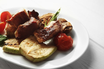 Grilled meat with vegetables on plate, closeup