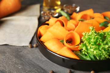 Plate with sliced carrot and lettuce on kitchen table