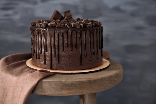 Tasty chocolate cake on chair on dark background