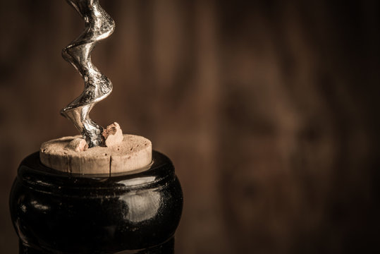 Bottle of wine with corkscrew on wooden background