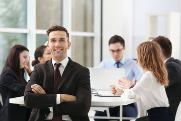 Businessman with colleagues on background at office