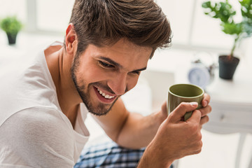 Dreamful man drinking coffee at home