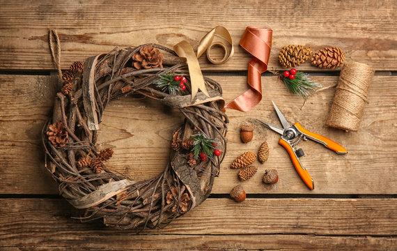 Decorative wreath and florist equipment on wooden background