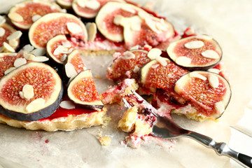 Delicious fig cake with almond flakes on parchment, closeup