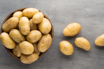 Fototapeta na wymiar New potato on the bowl, gray background.