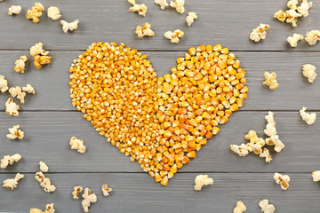 Heart made of maize grains on wooden background, top view