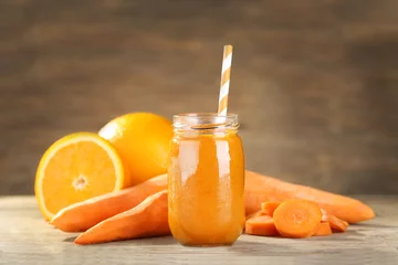 Fotobehang Sap Jar with carrot and orange smoothie on wooden table