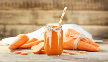 Fresh carrot smoothie and vegetables on wooden wall background