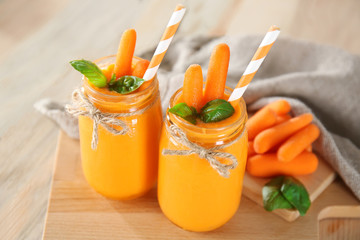 Glass jars with carrot smoothie on wooden table