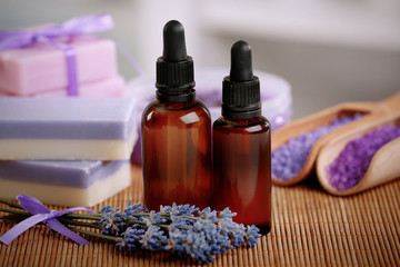 Bottles with lavender essential oil on bamboo mat, closeup
