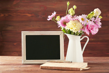 Vintage brown frame with flowers in vase on brown wooden background