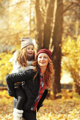 Mother and daughter playing in beautiful autumn park