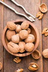 Walnuts in wooden bowl on table with Nutcracker. Top view.