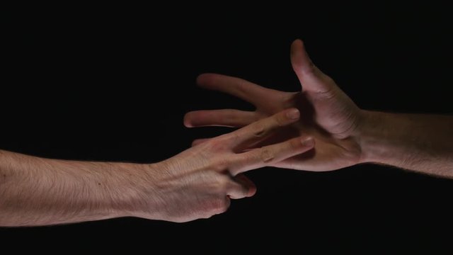Two hands playing rock paper scissors. Black background.