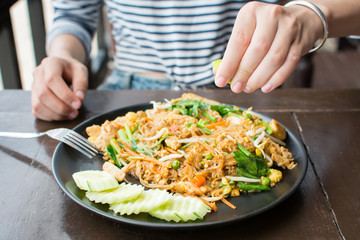 Female hand squeezing lime on Pad Thai