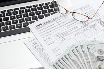 U.S. 1040 tax return form with laptop, cash and glasses