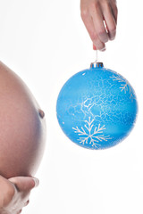 Живот беременной женщины с новогодним большим шаром на белом фоне, крупный 