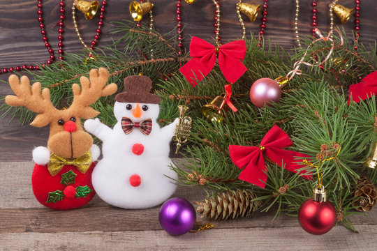 Christmas composition of fir branches decorated bows and balls with snowman reindeer on a wooden background