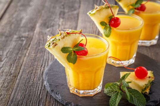 Glasses of pineapple juice with pieces of pineapple