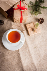 Gift wrapping and letters, cards for Christmas greetings. Envelopes with letters, gifts, Christmas tree branches and pine cones are on a wooden table lie, a cup of fragrant hot tea, top view