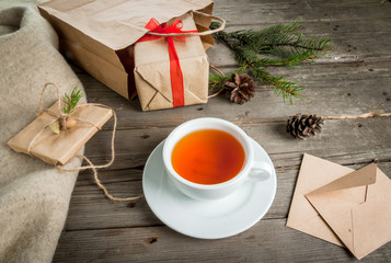 Gift wrapping and letters, cards for Christmas greetings. Envelopes with letters, gifts, Christmas tree branches and pine cones are on a wooden table lie, a cup of fragrant hot tea, top view