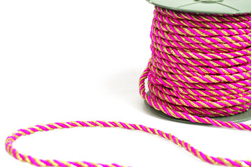 Spool of bright pink decorative cord on white background