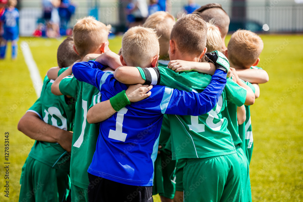 Wall mural Young football soccer players in sportswear. Young sports team with football coach. Pep talk with coach before the final match. Soccer school tournament