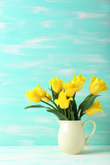 Bouquet of yellow tulips on a mint wooden background