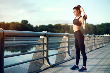 Attractive and strong woman stretching before fitness on the lake in the summer. Sports concept....