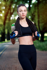 Young beautiful and strong woman resting after an active workout at the summer park. Sports concept. Healthy lifestyle