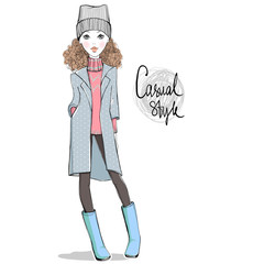 Lovely girl in autumn-winter clothes. Hand drawn cute teen with casual apparel. Hipster illustration. Personage in sketch style. Casual look. Vector girl in raincoat, hat, boots, sweater, pants.
